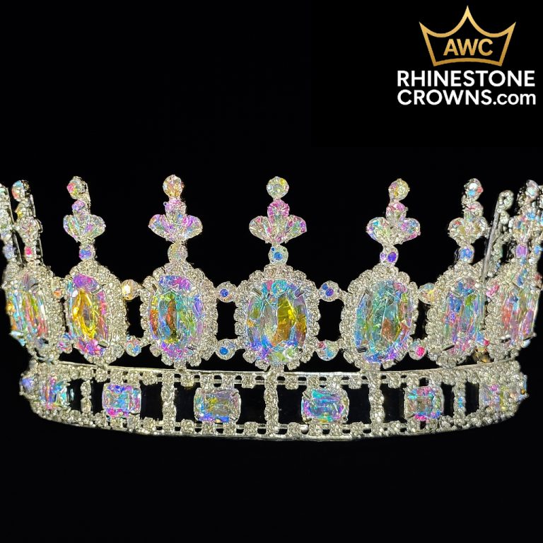 The Kimmy Series - 3"x6.25" Fully Round Crown sparkles with iridescent oval and rectangular gems against black. Ideal as a bridal crown, it showcases intricate details and the AWC Rhinestone Crowns logo appears in the upper right corner.