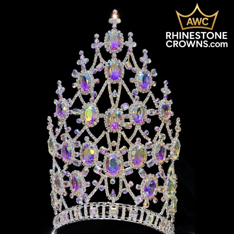 The Christmas Alessandra Series - 8.5" Crown is a tall, ornate rhinestone crown with large iridescent oval gems and intricate lattice design, perfect for pageants or prom; shown on a black background with the AWC logo and RhinestoneCrowns.com in the top right corner.