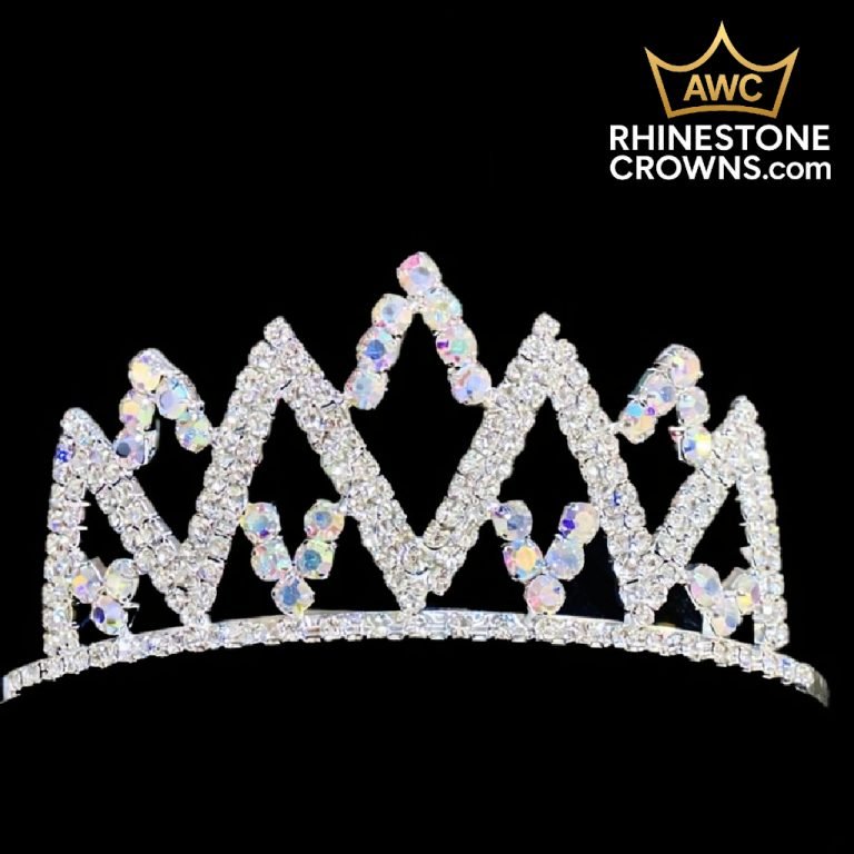 The Crystal AB Melissa Series - 2" Wide Span Crown, adorned with sparkling zigzag rhinestones and iridescent gems, is shown on a black background. AWC RHINESTONE CROWNS.COM and a gold crown logo are in the top right corner.