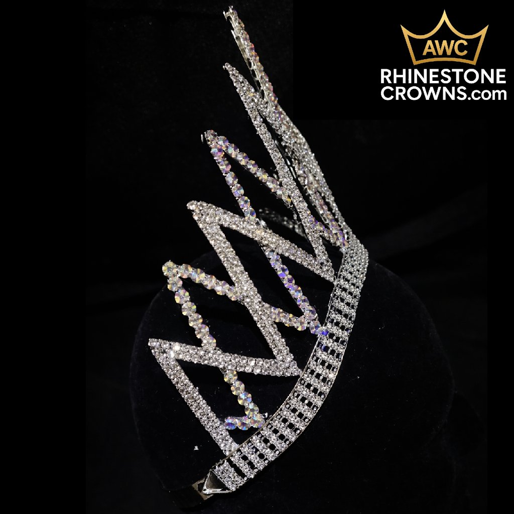 The Crystal AB Melissa Series-6" Wide Span, a sparkling rhinestone crown with zigzag peaks, sits on a black velvet display. The AWC RHINESTONE CROWNS.com logo is shown in the top right on a black background.