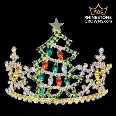 The Jingle All The Way Series-3" Wide Span Tiara features a sparkling rhinestone Christmas tree design with green, red, and gold jewels, topped with a star—perfect for festive pageants or dance. Displayed on black with the AWC Rhinestone Crowns logo above.