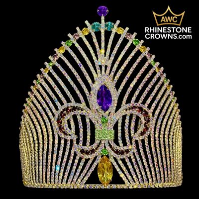 The Mardi Gras Majesty - 8" Crown features a multicolored rhinestone fleur-de-lis design with purple, yellow, and green gems. In stock and ready to ship, with more in production. AWC RhinestoneCrowns.com logo on black background (top right).