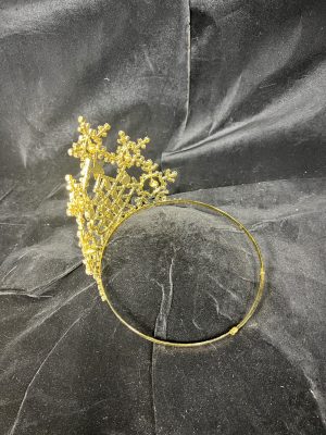 The Jingle All The Way Series-5" Crown, featuring intricate floral designs and decorative gold details, rests on a black textured fabric background.